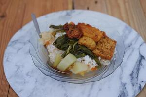 Rice with fried chicken and vegetables on a plate in a restaurant photo