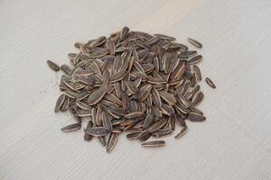 Sunflower seeds on wooden background. Heap of sunflower seeds photo