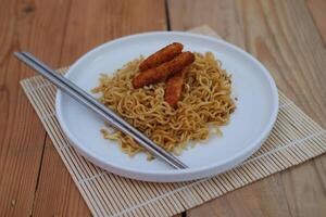 instante tallarines con pollo pepita y palillos en un de madera mesa. foto