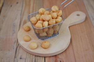 a traditional cake from Indonesia called kue sus filled with cream puffs. served on metal basket on wooden board photo