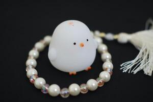 chicken toy with a pearl necklace on a black background close up photo