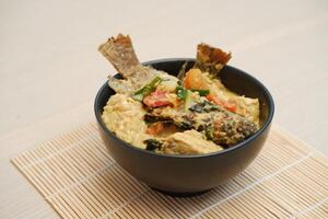 Fried fish with curry in a bowl on a bamboo mat. photo