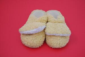 Soft yellow slippers resting on bright red floor. photo