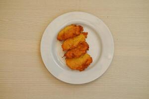 maíz croquetas en un blanco plato en un de madera mesa foto