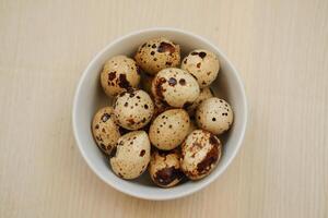 Quail eggs in a bowl on a wooden background. Selective focus. photo