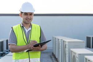 asiático mantenimiento ingeniero trabajos en el techo de fábrica. contratista inspeccionar compresor sistema y planes instalación de aire condición sistemas en construcción. Lista de Verificación, inspector, controlar foto