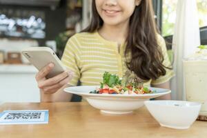 Woman use smartphone to scan QR code to pay in cafe restaurant with a digital payment without cash. Choose menu and order accumulate discount. E wallet, technology, pay online, credit card, bank app. photo