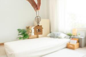 Moving house, relocation. man hold key house keychain in new apartment, inside the room was a cardboard box containing personal belongings and furniture. move in the apartment or condominium photo