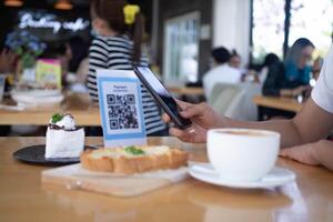 Woman use smartphone to scan QR code to pay in cafe restaurant with a digital payment without cash. Choose menu and order accumulate discount. E wallet, technology, pay online, credit card, bank app. photo