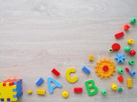 A colorful assortment of building blocks and letters, including are scattered across a wooden surface photo