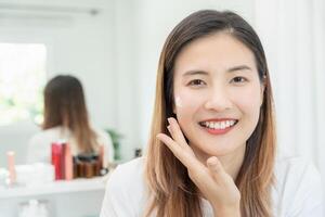 hermosa asiático mujer sonrisa utilizar crema para bueno piel. cara de un sano mujer aplicar crema y constituir. anuncio para piel crema, anti arrugas, bebé rostro, blanqueo, hidratante, apretar poros suero foto