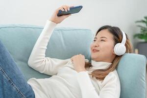 Joyful young Asian women in wireless headphones sitting and enjoy music, having fun, listening to music, raising his arm, dancing to favorite song, enjoying cool soundtrack, happy life, recreation photo