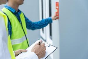 Contactor or engineer is inspecting construction and quality assurance new house using a level. Engineers or architects or contactor work to build the house before handing it over to the homeowner photo