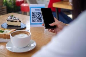 la mujer usa un teléfono inteligente para escanear el código qr para pagar en un café restaurante con un pago digital sin efectivo. elige menú y ordena acumula descuento. billetera electrónica, tecnología, pago en línea, tarjeta de crédito, aplicación bancaria. foto