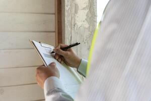 el inspector o ingeniero está inspeccionando la construcción y el aseguramiento de la calidad de la nueva casa usando una lista de verificación. ingenieros o arquitectos o contratistas trabajan para construir la casa antes de entregársela al propietario foto