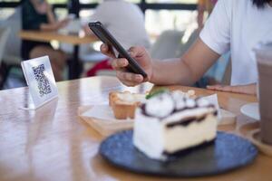 Woman use smartphone to scan QR code to pay in cafe restaurant with a digital payment without cash. Choose menu and order accumulate discount. E wallet, technology, pay online, credit card, bank app. photo