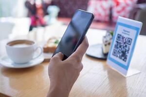 Woman use smartphone to scan QR code to pay in cafe restaurant with a digital payment without cash. Choose menu and order accumulate discount. E wallet, technology, pay online, credit card, bank app. photo