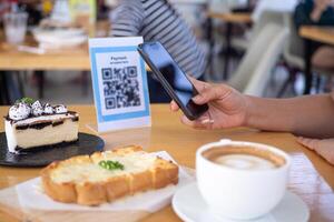 la mujer usa un teléfono inteligente para escanear el código qr para pagar en un café restaurante con un pago digital sin efectivo. elige menú y ordena acumula descuento. billetera electrónica, tecnología, pago en línea, tarjeta de crédito, aplicación bancaria. foto