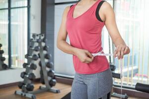 dieta y dieta. cinta métrica de uso de cuerpo femenino delgado de belleza. mujer con ropa de ejercicio logra el objetivo de pérdida de peso para una vida saludable, loca por la delgadez, cintura delgada, nutricionista. foto