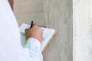 el inspector o ingeniero está inspeccionando la construcción y el aseguramiento de la calidad de la nueva casa usando una lista de verificación. ingenieros o arquitectos o contratistas trabajan para construir la casa antes de entregársela al propietario foto