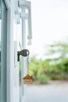 Landlord key for unlocking house is plugged into the door. Second hand house for rent and sale. keychain is blowing in the wind. mortgage for new home, buy, sell, renovate, investment, owner, estate photo