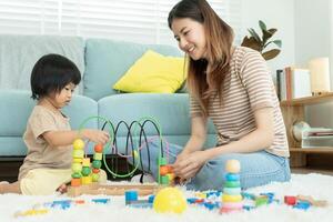 Happy Asia mother play and learn toy blocks with the little girl. Funny family is happy and excited in the house. Mother and daughter having fun spending time together. Holiday, Activity, development photo