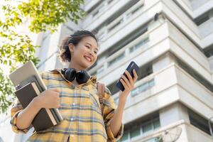 Beautiful student asian woman with backpack and books outdoor. Smile girl happy carrying a lot of book in college campus. Portrait female on international Asia University. Education, study, school photo