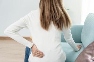 mujer participación su inferior espalda mientras y sufrir desde inaguantable dolor salud y problemas, crónico espalda dolor, dolor de espalda en oficina síndrome, escoliosis, herniado desct, músculo inflamación foto