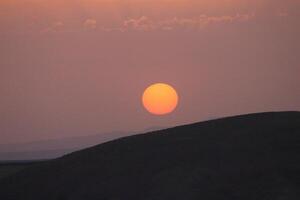 a sunset with clouds and a orange sun setting in the sky. photo