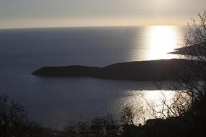 The sea surface of the Adriatic Sea. An island with green trees. View from above. Montenegro. Budva. Horizontal. photo