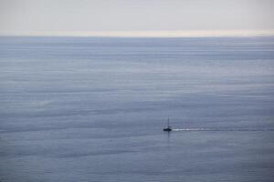 A small sailing boat sails on the sea surface of the Adriatic Sea. Balkans. View from above. Montenegro. Budva. Horizontal. photo