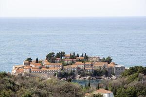 Sveti Stefan Island in the Adriatic Sea, Montenegro. Island with houses and trees. See through the trees from above. Balkans. Background photo