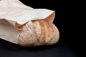 Vermont black flour rye bread with a crispy crust and a spongy texture. Freshly baked homemade bread in a Kraft paper bag. Photo in high quality.