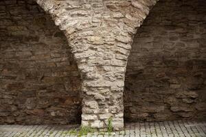 Old brick wall with semicircular arches. Weathered surface of the wall. Grunge style brick wall background. Weathered facade of a building. Horizontal. photo