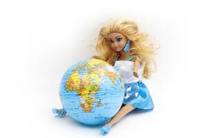 Model of the world lying on its side, globe or Earth. A doll sits next to the globe. Isolated on white background. Africa, Europe, India, Turkey, Iran, Iraq. Horizontal. For text. photo