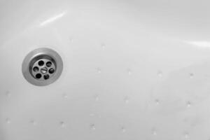 Detail of a ceramic white sink in a modern bathroom with chrome plated drain. Horizontal. For text. photo