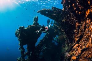 Woman free diver swim with fins at wreck ship. Freediving in ocean photo