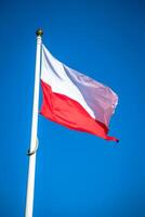 Polish flag on a pole against blue sky photo