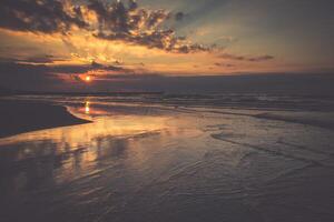 Sunset on beach with a wooden breakwater in Leba, Baltic Sea, Poland photo