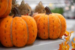 Close-up and selective focus of a woolen Halloween pumpkin on a shelf in a supermarket. DIY, craft decoration for fall. Autumn decoration with handmade colorful fabric pumpkins. photo