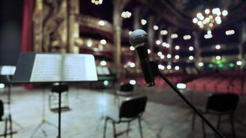 A microphone and a sheet music stand in front of a stage photo