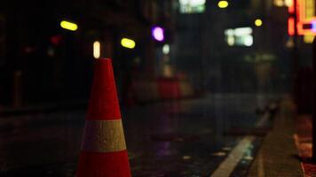 Bright Neon Traffic Cone on the Side of Rainy Asian City Road photo