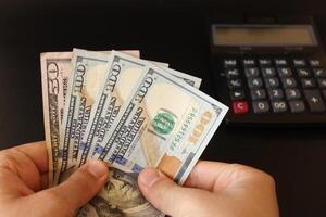 man counting US dollars money with his hand. US banknotes. The paper currency of usa .Calculator in the background. photo