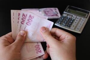 turco 200 lira billetes.hombre contando turco dinero con su calculadora.de.mano en el antecedentes. el papel moneda de pavo. foto