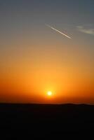 airplane and its trail in the sky. clouds and different color tones in the sky at sunset. Amazing and incredible sunset. photo