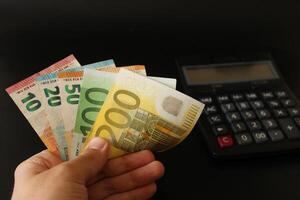 man counting euro money with his hand. euro banknotes. The paper currency of europan union .Calculator in the background. photo