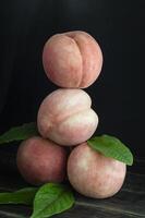 peaches stacked on top of each other with leaves photo