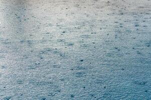 Defocus blurred transparent blue colored clear calm water surface texture with splashes and bubbles. photo