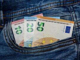 10, 20 and 50 euro bills coming out of the back pocket of a pair of jeans 1 photo