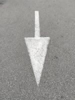 blanco flecha pintado en urbano calle asfalto. indicando dirección. foto